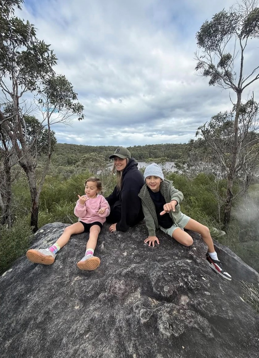 Jessie with her children Koda and Kylo, outdoors on a rock.