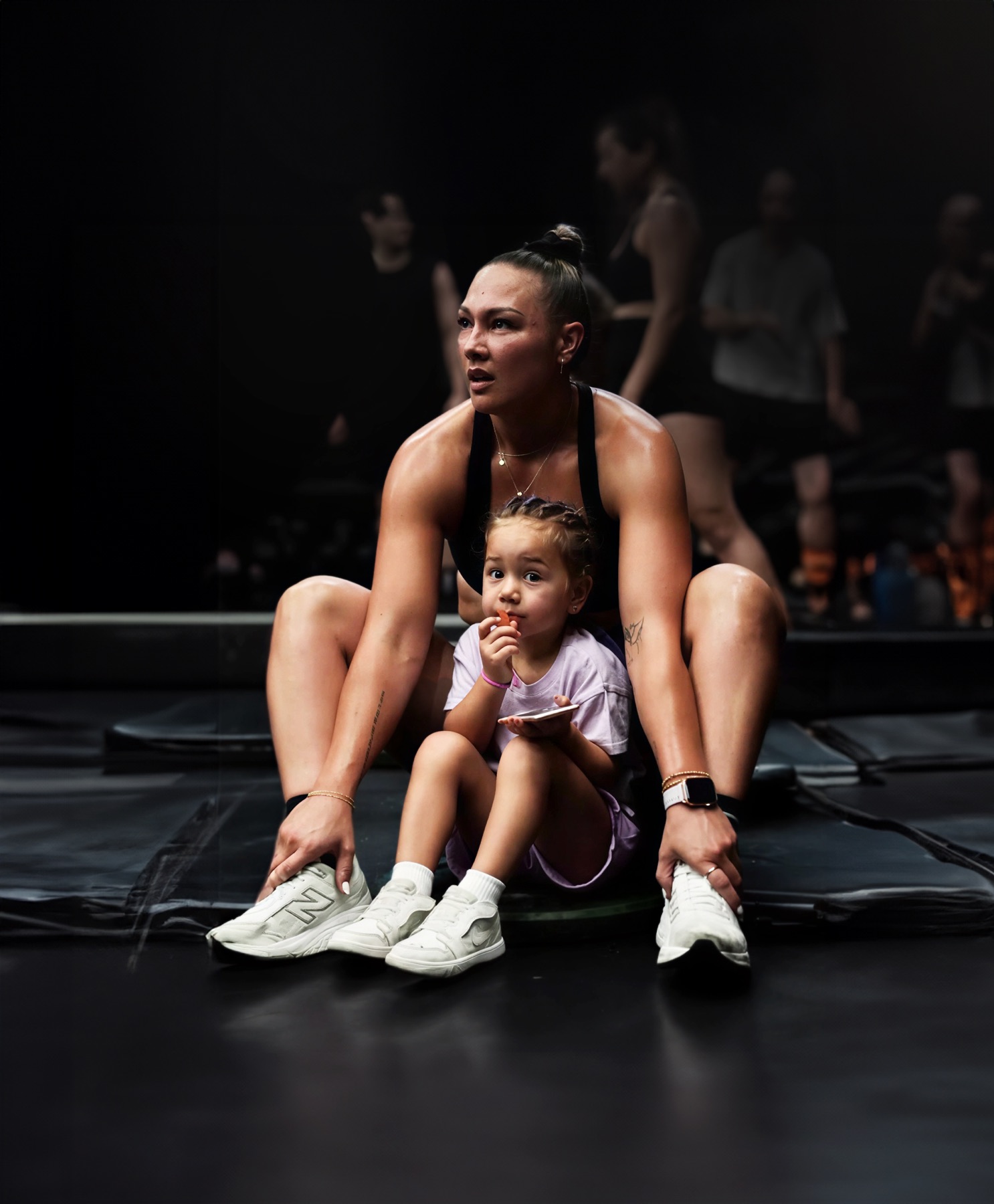 Jessie Wharepouri in a deep squat, her daughter sitting between her feet.